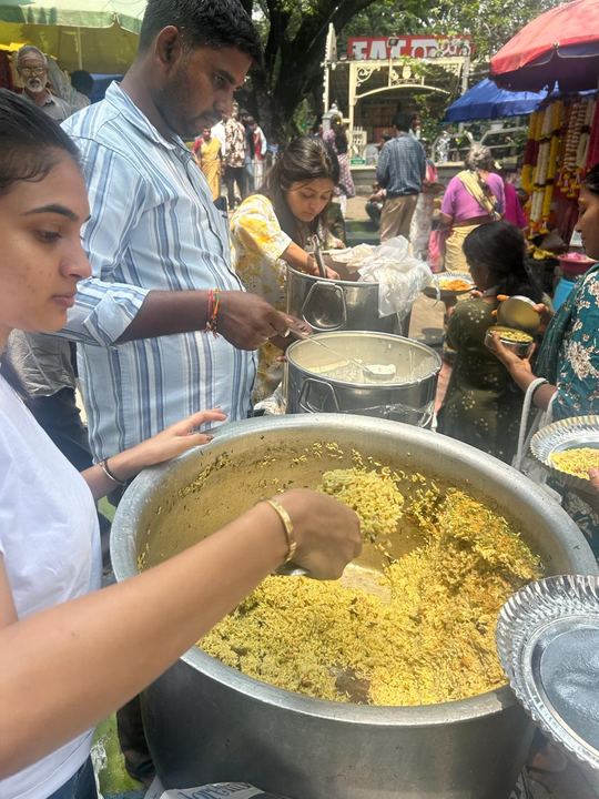 A volunteer scooping rice onto plates while people wait to be served