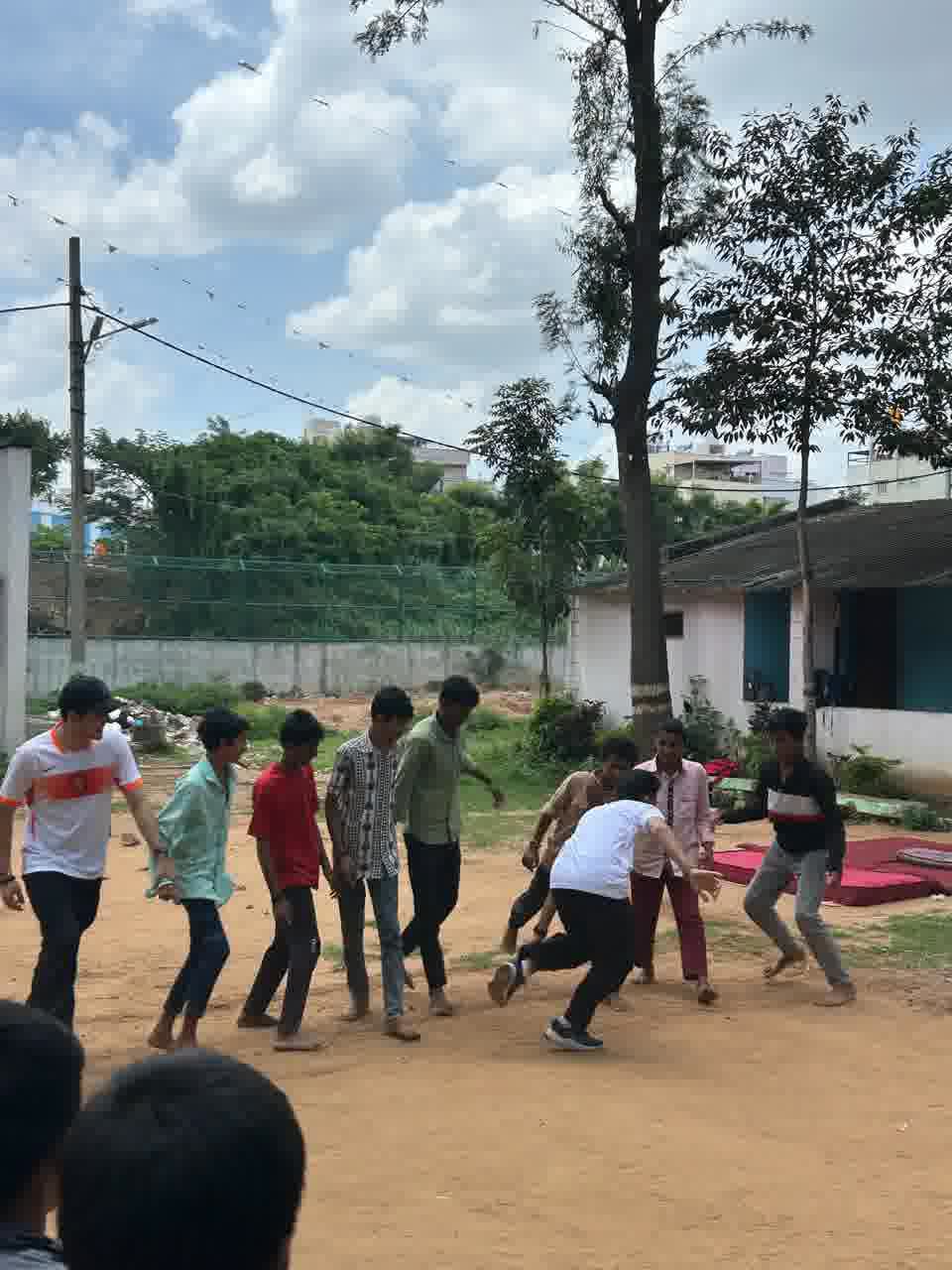 Boys playing kabaddi on the ground outside the ashram