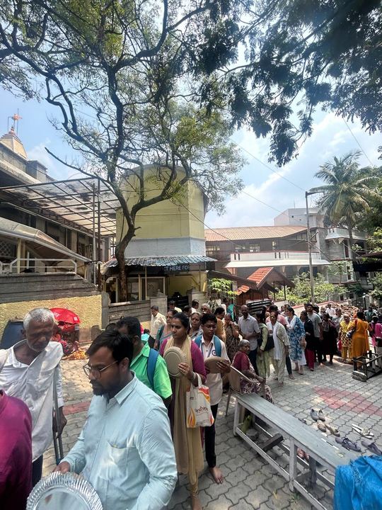 Devotees standing in a queue with paper plates in the temple courtyard